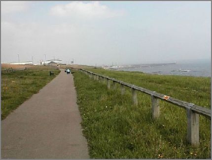 About half a mile south of the Dock Company roundabout. At this point the road is about 200 yards west (off to the left) of the walkway.