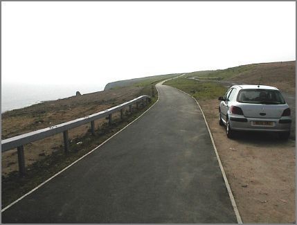 The walkway continues to hug the coastline as the road begins to gradually sweep westwards.  The walkway stretches south towards Noses Point and the impressive Blast Beach. There is also visible the (rougher) driveway which runs alongside the walkway and offers easy car or disabled access to the Noses Point Car Park. We will follow the walkway to the Blast Beach and then return to this point to follow the road.