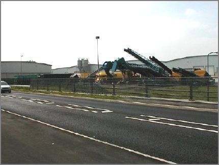 It is a this point that an underpass from the Dock Companys premises runs under the George Elmy Lifeboat Way. The large machines are located within the Dock Company premises and some of the large warehouses can be seen.