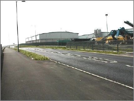More views of the Dock Company warehouses and machinery.  In the distance the road curves up towards the roundabout at the entrance to the Dock Company premises and where the walkway parts company with the road and continues south hugging the coastline as the road bends slowly westwards.