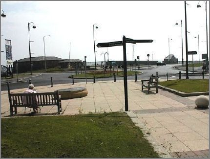 A slightly different view south from Millenium Clock  corner. A car can be seen proceeding northwards along The George Elmy Lifeboat Way. The building in the distance is the former Coastal Center which was much used by schools from all over the north east to view the dock activities and study coastal features.